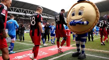 Crusty, the Wigan mascot, welcomes the Fulham squad to the Brick Community Stadium