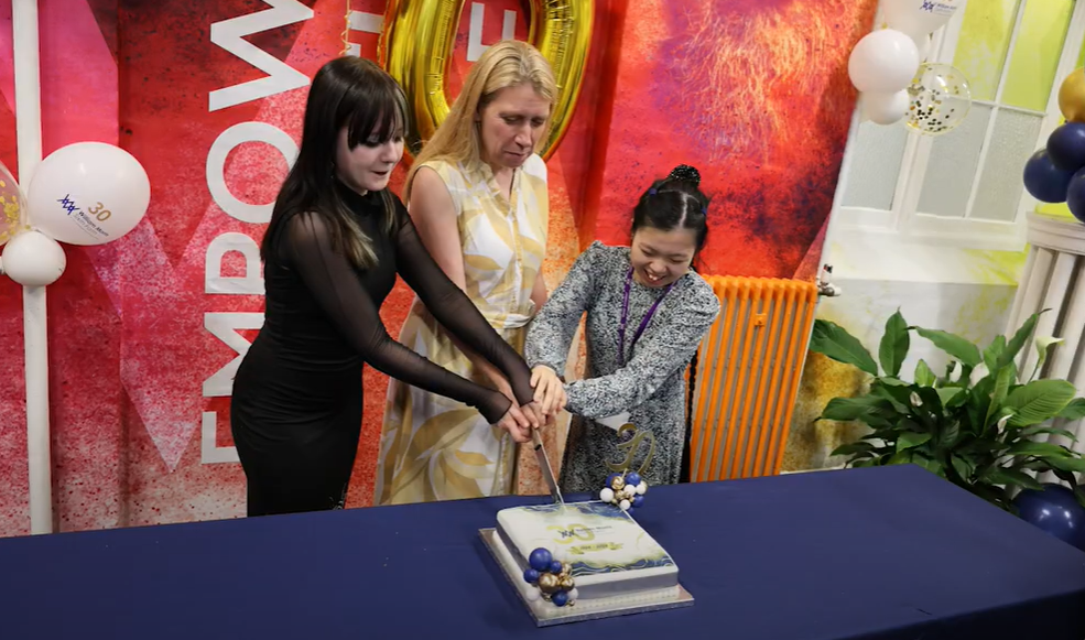 Mary Berrisford, school principal (centre) cuts celebration cake with students