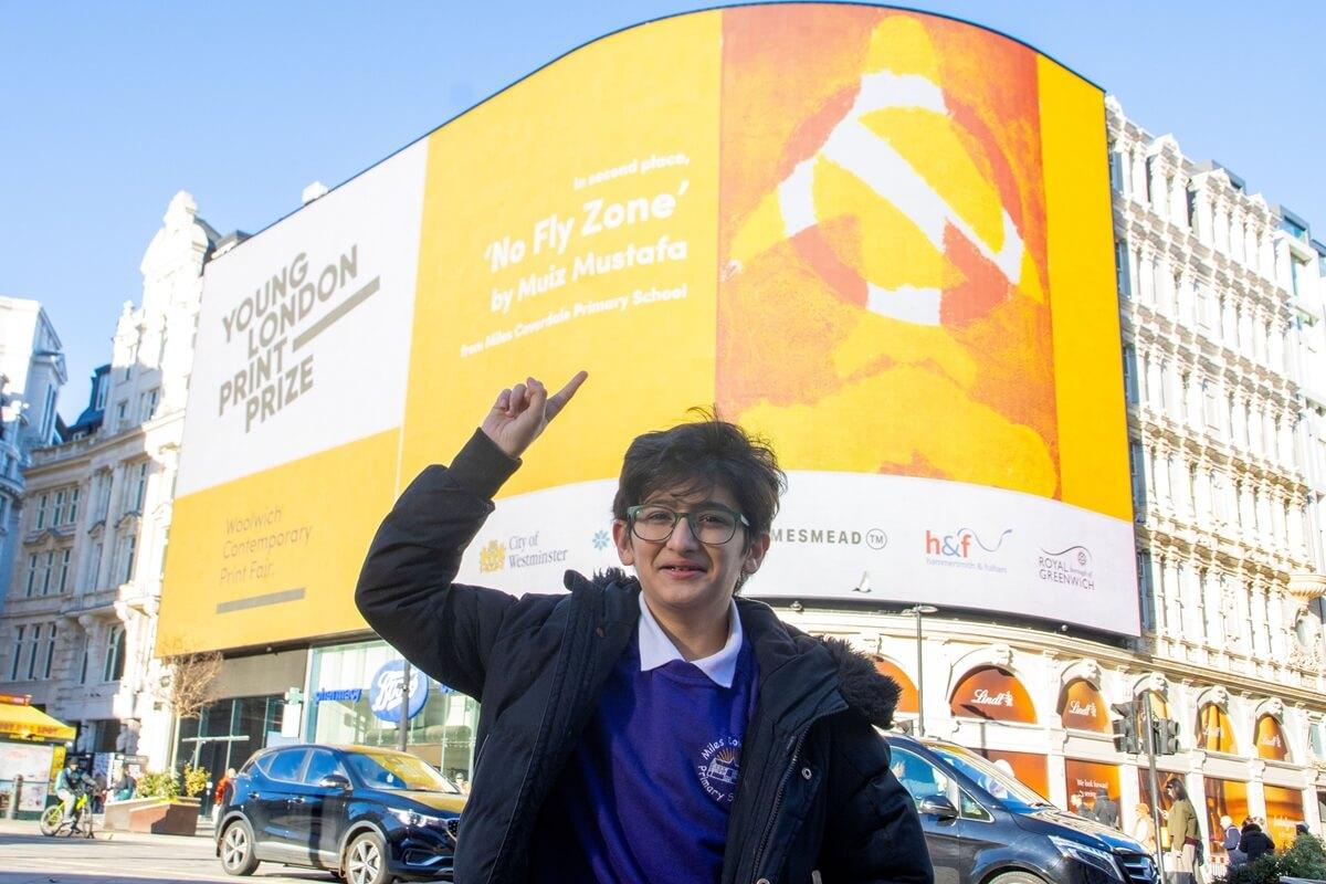 Muiz Mustafa showing off his winning print 'No Fly Zone' in Piccadilly Circus