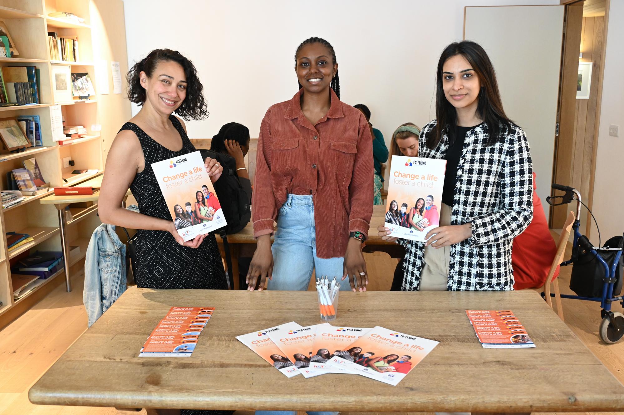 Three H&F Fostering Officers stand next to a table at a Foster Care Fortnight coffee morning