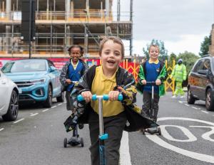 Kids on scooters on a street.