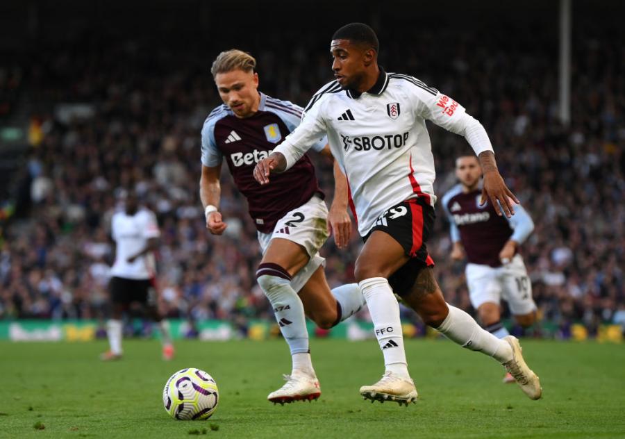 Reiss Nelson runs with the ball whilst under pressure from Matty Cash